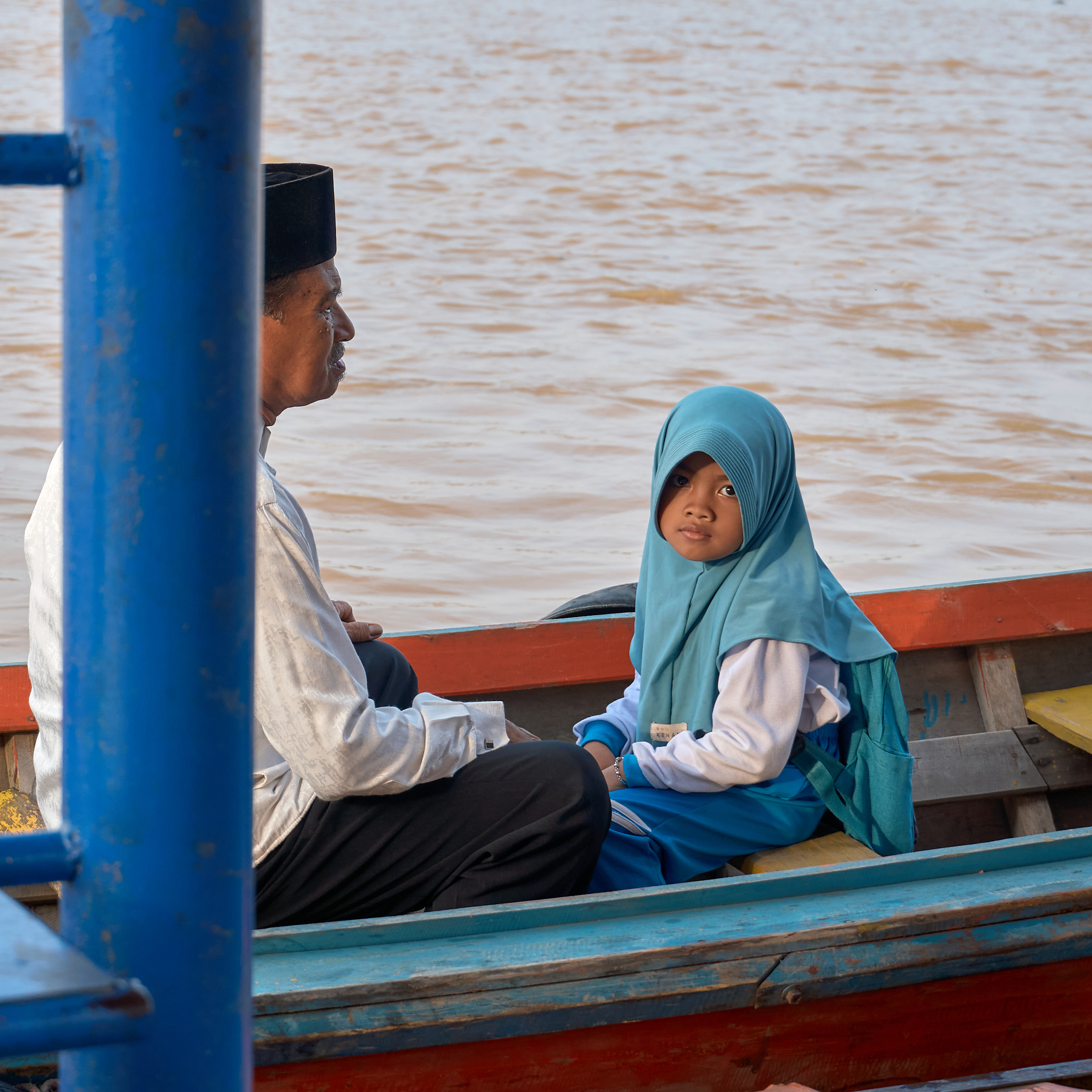 A child and adult riding a wooden boat